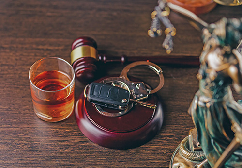 Gavel, glass of liquor, car keys, and handcuffs, representing DUI defense from the Law Offices of Matthew Cargal